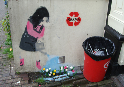 Graffiti image showing little girl watering flowers with a Karma sign next to her