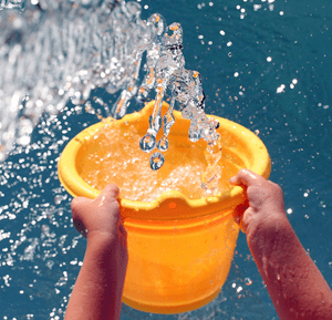 Water being tossed out of a bucket in sunshine