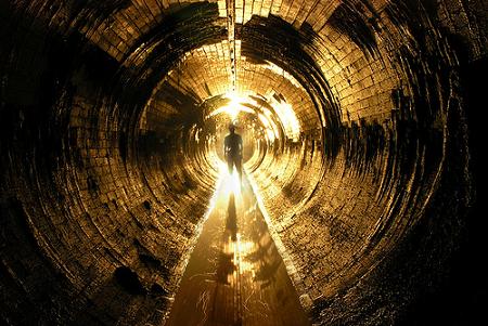 Backlit figure in sewer tunnel