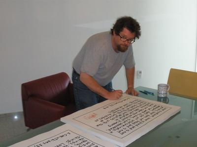 Hugh MacLeod signing prints of his work.