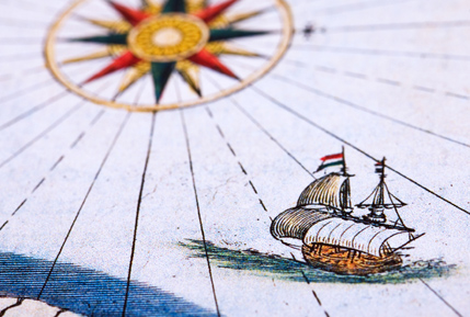 Ship sailing across antique map towards compass