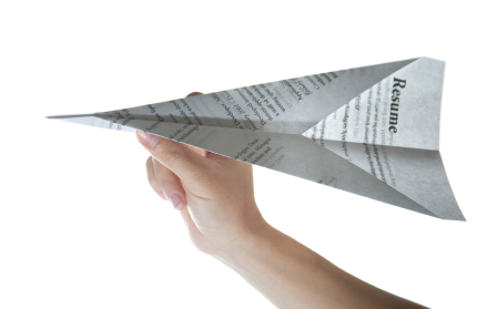 Hand holding a resume folded into a paper aeroplane
