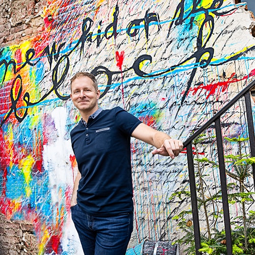 Robert Vlach in front of wall of graffiti