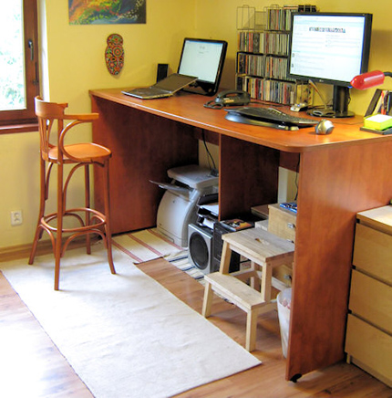 High desk set up with two computers, one with a high chair and the other with no chair, for working while standing
